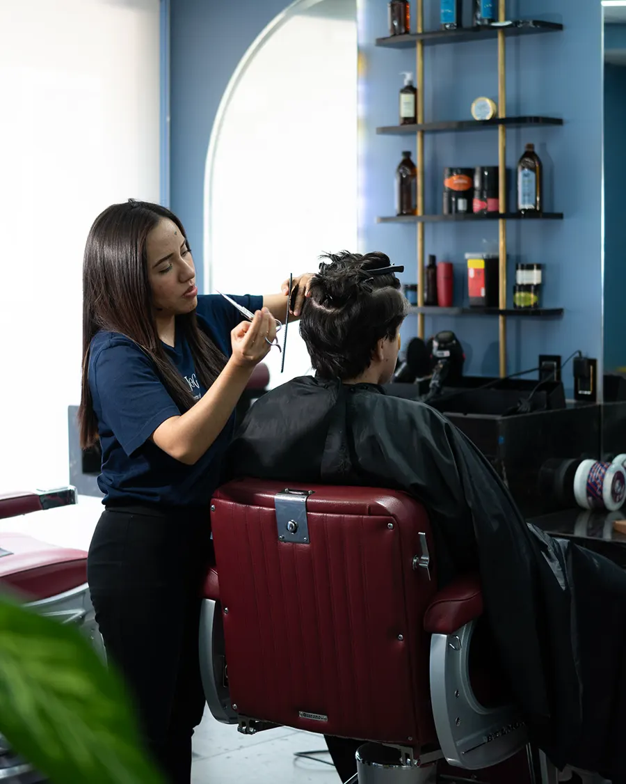 Estilista cortando el cabello a un cliente en una barbería